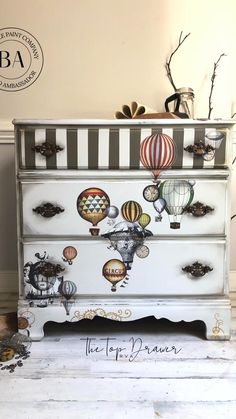 an old dresser has hot air balloons painted on the front and sides, along with other decorations