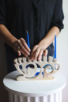 a person holding two candles in front of a cake