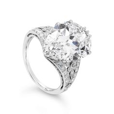 an oval cut diamond ring with filigrees on the shoulders and sides, set in