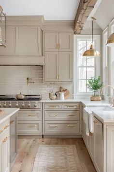 a kitchen with lots of white cabinets and gold accents on the counter tops, along with wooden flooring