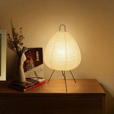 a white lamp sitting on top of a wooden table next to a vase and book