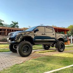 a black truck parked on top of a lush green field next to a brick walkway