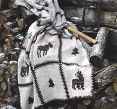 a blanket with horses on it sitting next to logs and a lantern in the background