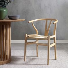 a wooden chair next to a table with a vase on it and a bowl in the background