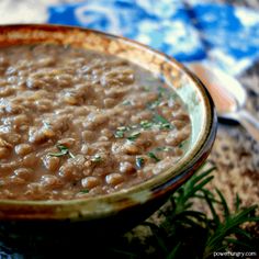 a close up of a bowl of food with beans and herbs in it on a table