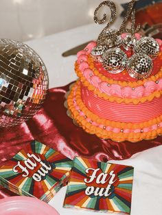 a table topped with a pink cake and disco ball next to two cards that say eat out