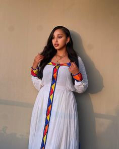 This beautiful Habesha dress is a perfect example of the understated elegance that is so characteristic of Ethiopian fashion. The dress features the soft and luxurious Menen fabric, which is known for its incredible quality and comfort. The simple Shimena design is timeless and classic, with a flattering A-line silhouette that skims the body and accentuates the curves in all the right places. The real star of the show, however, is the intricate Tilf accents that adorn the dress. These delicate p White Bohemian Long Sleeve Habesha Kemis, Bohemian White Long Sleeve Habesha Kemis, Traditional White Habesha Kemis For Festival, Folk Style White Habesha Kemis For Festival, White Folk Style Habesha Kemis, White Habesha Kemis For Festival, White Habesha Kemis With Traditional Patterns For Festival, White Folk Habesha Kemis For Traditional Ceremonies, White Bohemian Habesha Kemis