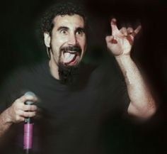 a man holding a microphone up to the side with his mouth wide open and tongue out