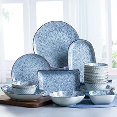 a blue and white dinnerware set on a wooden board with windows in the background