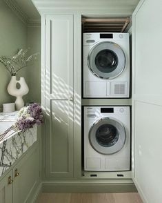 a washer and dryer are in the corner of a room with green walls