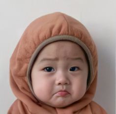 a baby wearing a hoodie looking at the camera