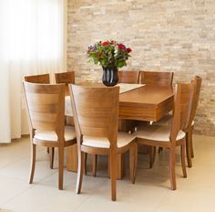 a dining room table and chairs in front of a brick wall with flowers on it