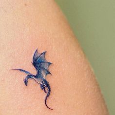 a small blue dragon tattoo on the arm