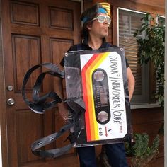 a man is holding an old school tape recorder costume and wearing goggles while standing in front of a door