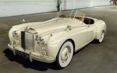 an old fashioned white car parked in a garage