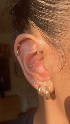 a woman's ear with three different piercings on the top and bottom of it