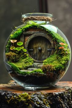 a glass jar filled with moss and a small door in the middle on top of a tree stump