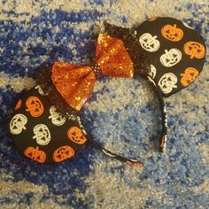 a minnie mouse ears with pumpkins and skulls on it, sitting on a blue carpet