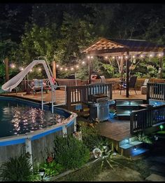 an outdoor swimming pool at night with lights on the deck and in ground hot tub