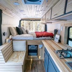 the interior of an rv with wood flooring and blue cabinets, including a bed