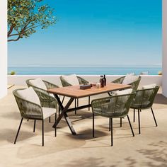 an outdoor dining table and chairs on a patio with the ocean in the back ground