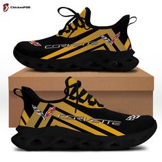 a pair of black and yellow sneakers with the word corvette on them, in front of a cardboard box