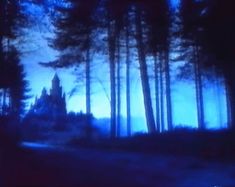 a blurry image of a castle in the woods at night with blue light coming from it's windows