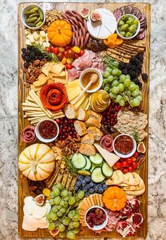 a wooden platter filled with lots of different types of cheeses and meats