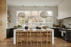 a kitchen with wooden floors and white counter tops next to an island in front of a window