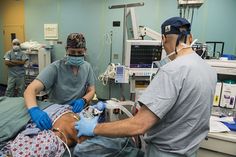 two men in scrubs and surgical masks operating on an iv / occupent