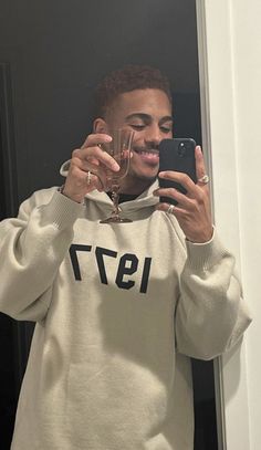 a man taking a selfie in front of a mirror wearing a sweatshirt with the number 1971 on it