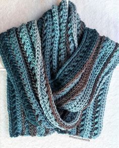 a blue and brown knitted scarf hanging from a hook on a white carpeted wall