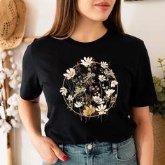 "Flower Shirt, Gift For Her, Flower Shirt Aesthetic, Floral Graphic Tee, Floral Shirt, Flower T-shirt, Wild Flower Shirt, Wildflower Tshirt ⭐Please Check All Photos For Details. 🐞Choose Your T-Shirt Size From The Drop-Down Lists Next To The item Picture ⭐Choose Of Your T-Shirt Color From The 2nd Picture 🐞Use \"Add message to Seller\" link On The Checkout Page To Send me the Following important Details For Your Order's Customization. ⭐Shipping Time Varies by location (we are located in Sugar La Black Crew Neck T-shirt With Plant Print, Botanical Short Sleeve T-shirt With Floral Embroidery, Botanical Style T-shirt With Floral Embroidery, Botanical Style Short Sleeve T-shirt With Floral Embroidery, Floral Embroidered Crew Neck Graphic Tee, Botanical Crew Neck Top With Graphic Print, Botanical Top With Floral Embroidery And Relaxed Fit, Botanical Printed Crew Neck Top, Botanical Crew Neck Top With Floral Embroidery