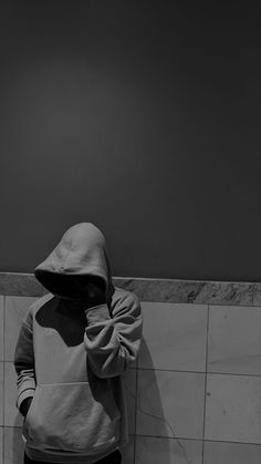 a person in a hoodie standing against a wall