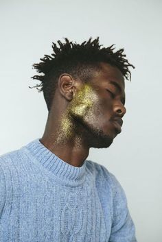 a man with gold paint on his face and hair is looking down at the camera