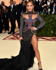 a woman in a black and blue dress with feathers on the skirt is posing for photographers