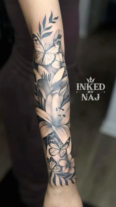 a woman's arm with flowers and butterflies tattooed on the side of her arm