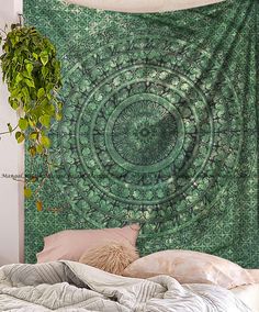 a large green tapestry hanging on the wall above a bed with pillows and blankets in front of it