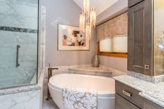 a bathroom with marble counter tops and a tub in the middle, surrounded by cabinets