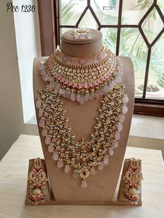 an elaborate necklace and earring set on display in front of a window with glass panes