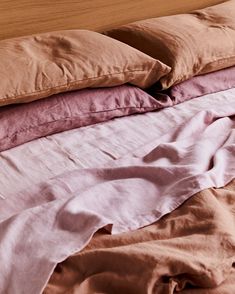 an unmade bed with pink and brown sheets