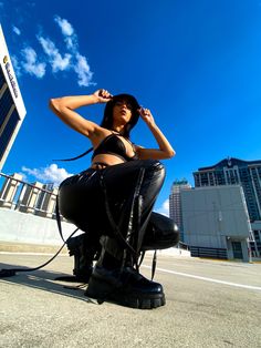 a woman is sitting on the ground with her hat over her head and wearing all black