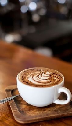 a cappuccino is sitting on a wooden tray