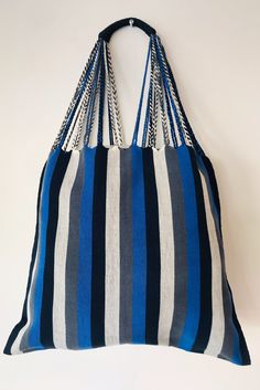 a large blue and white striped bag hanging on a wall with chains attached to it