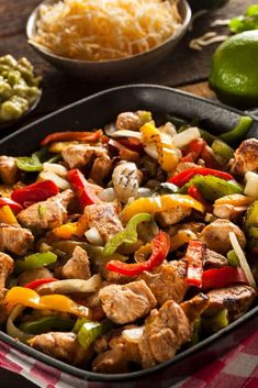 a skillet filled with meat and vegetables on top of a table next to other foods