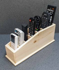 a wooden holder with remotes and cell phones in it