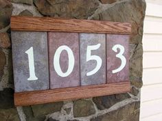 a house number sign mounted to the side of a stone wall