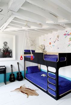 there is a bunk bed in the room with blue bedspreads and guitars on the wall