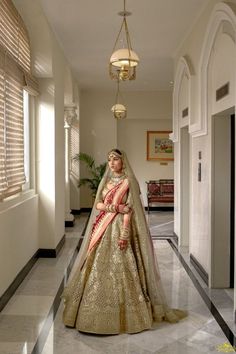 a woman in a gold and red bridal gown posing for the camera with her hands on her hips