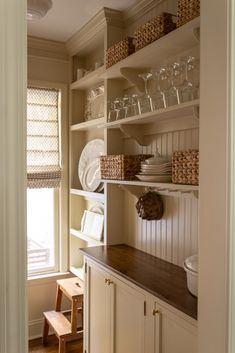 a kitchen with white cabinets and shelves filled with dishes